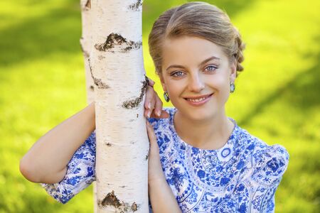 Close up portrait of a beautiful young blonde woman in blue dress, outdoorsの写真素材