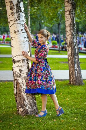 Portrait of Beautiful blond woman on a tree in autumn parkの写真素材