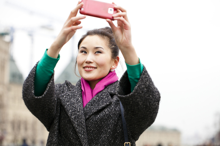 Young beautiful woman tourist taking pictures on mobile phone on the background Red Square, Moscow Kremlin, Russiaの写真素材