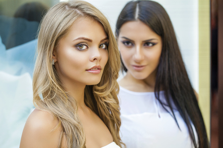 Glamorous portrait of two young beautiful women. Blonde and brunette women, indoorの写真素材