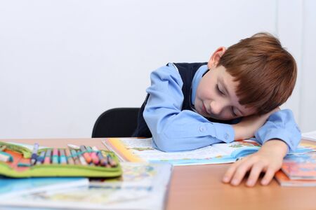 beautiful little boy sleeping on the tableの写真素材