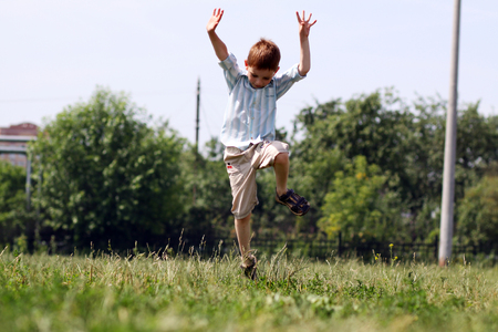 little boy runs in a summer parkの写真素材