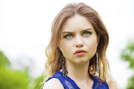 Close up Portrait, Young beautiful blonde woman posing outdoors in summer green parkの写真素材