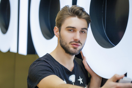 Young handsome man in a black knitted sweater photographing themselves on a cell phone