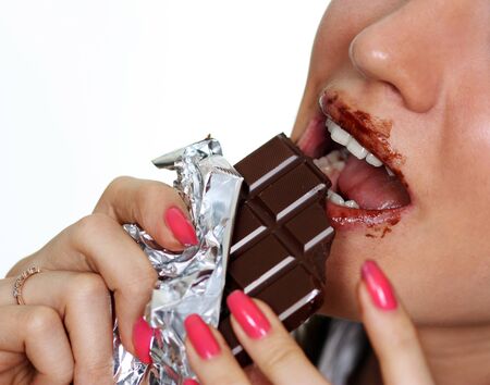 Young woman eating a chocolate candy, isolated on white