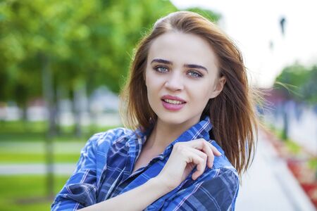 Portrait close up of young beautiful woman in a checkered blue shirt, summer outdoorの写真素材