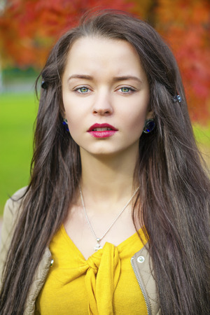 Close up Portrait, Young beautiful brunette woman posing outdoors in autumn parkの写真素材
