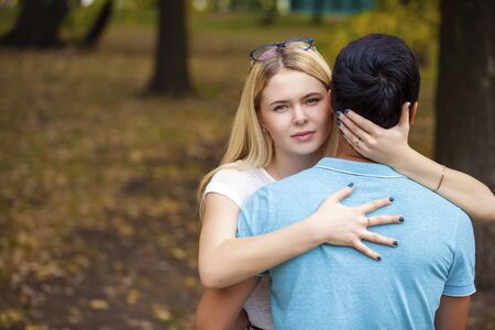 Close up portrait of attractive girl embracing her boyfriend outdoors.