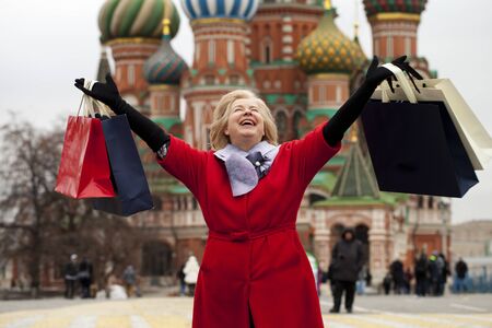 Mature happy blonde woman with shopping bags on Red Square in Moscowの写真素材