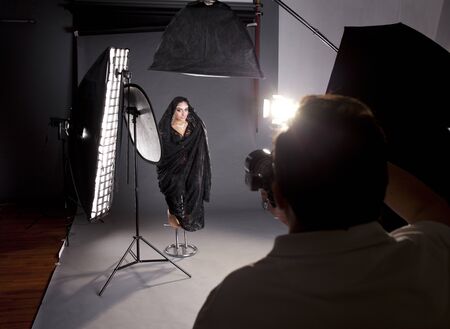 Working conditions in the studio, the photographer photographs the professional model, dark photo studioの写真素材