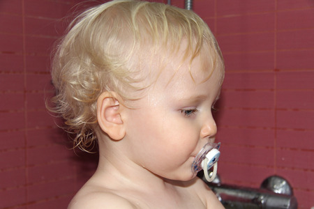 Curly wavy hair blond baby boy in bathroom