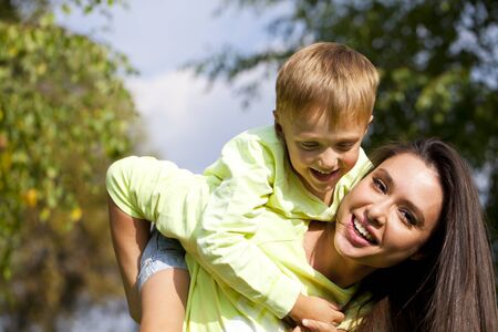 Happy Little boy and mother walking in autumn parkの写真素材