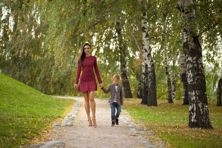 Happy Little boy and mother walking in autumn parkの写真素材