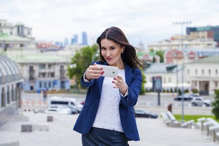 Beautiful young business woman calling by phone on the summer streetの写真素材