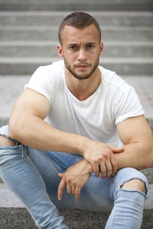 Handsome muscular young man posing on a stone steps backgroundの写真素材
