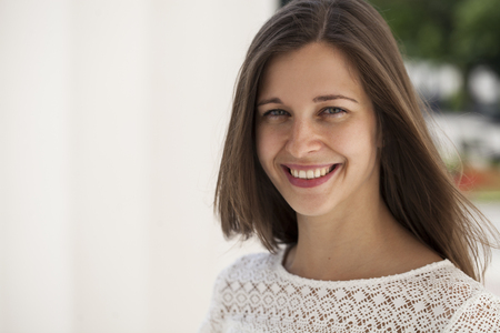 Closeup portrait of a happy young woman smiling, summer street outdoorsの写真素材