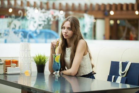 Young brunette woman drinking cocktail in a cafe indoorsの写真素材