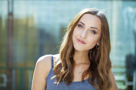 Close up portrait of beautiful young happy brunette woman with fresh and clean skin, summer street outdoorsの写真素材