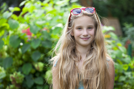 Portrait of a beautiful young little girl on the background of summer parkの写真素材