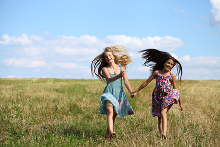 Two Happy little girls running in summer fieldの写真素材