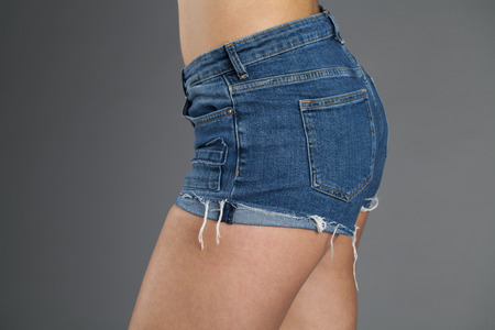 Body Part Sexy Female body. Sexy woman in blue jeans shorts isolated on gray backgroundの写真素材