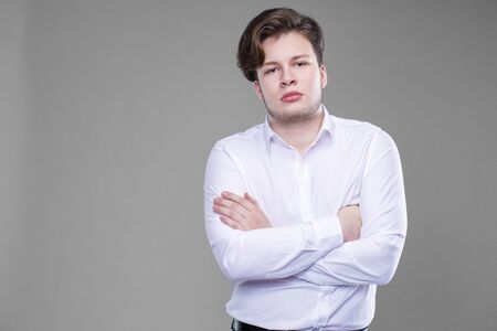 Elegant young handsome man in white shirt. Studio fashion portrait, isolated on gray backgroundの写真素材
