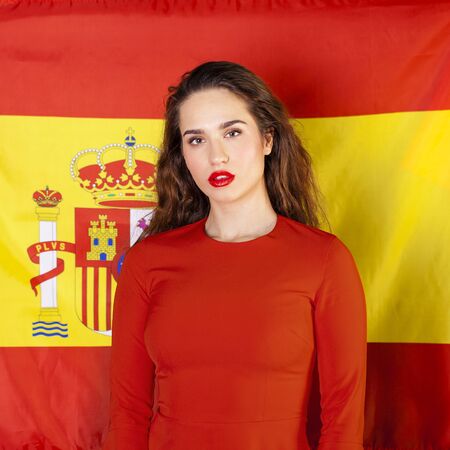 Young beautiful brunette woman on the background of the Spanish flagの写真素材