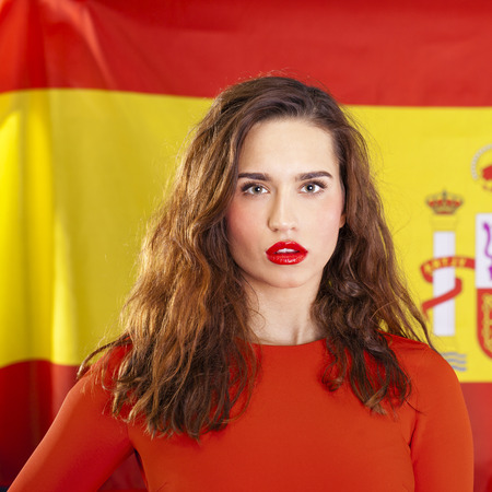 Young beautiful brunette woman on the background of the Spanish flagの写真素材