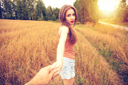 Follow me, Beautiful sexy young woman holds the hand of a man in a wheat fieldの写真素材