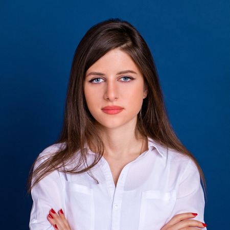 Happy brunette woman in white shirt, isolated on blue backgroundの写真素材