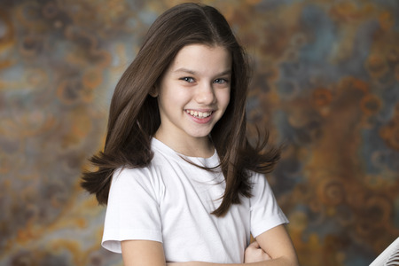Hair Style Wind. Portrait of a charming little girl on studio wall background