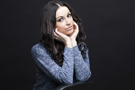 Close up portrait of a young woman. Beautiful brunette burning on isolated black backgroundの写真素材