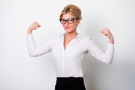 The strength of a woman in her weakness. Portrait of a beautiful young blonde woman in a white blouse on white wall backgroundの写真素材
