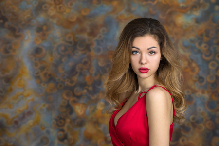 Portrait of beautiful young adult attractive sexy and sensuality happy pretty blonde woman in red elegance fashionable dress on studio wall backgroundの写真素材