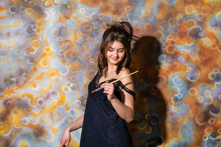 Art workshop. Young beautiful girl posing on the background of painted wallの写真素材