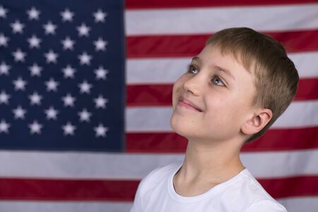 Portait of Caucasian little boy with American flag in backgroundの写真素材