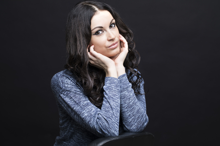 Close up portrait of a young woman. Beautiful brunette burning on isolated black backgroundの写真素材