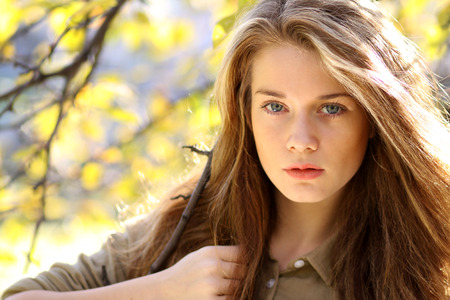 Portrait of a young beautiful blonde woman on a background of autumn parkの写真素材