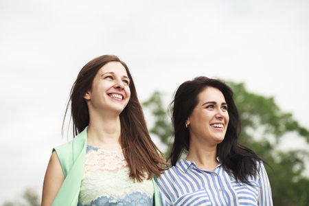 Two happy women walking in the summer parkの写真素材
