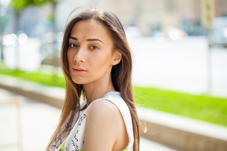 Close up portrait of beautiful young happy brunette woman with fresh and clean skin, summer street outdoorsの写真素材