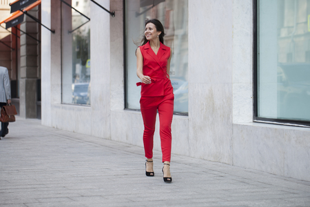 Portrait in full growth of a beautiful young woman in red suit, street summer outdoorsの写真素材