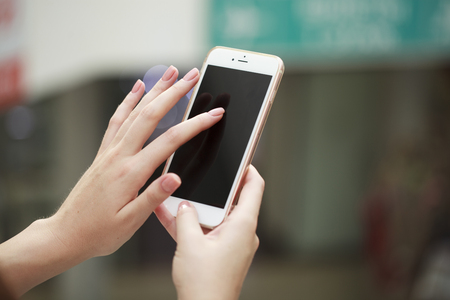 Beautiful female hands holding a mobile phone, indoorの写真素材