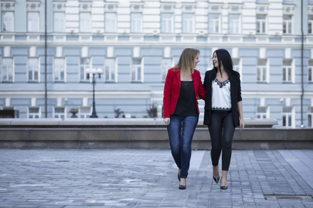 Two happy young women walking in summer street, outdoorsの写真素材