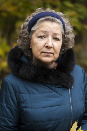 Portrait of a gray-haired elderly woman in an autumn parkの写真素材