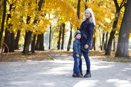 Young Mother and little son in autumn park. Concept of friendly family.の写真素材