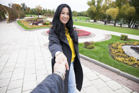Follow me, Beautiful sexy young woman holds the hand of a man in autumn city parkの写真素材