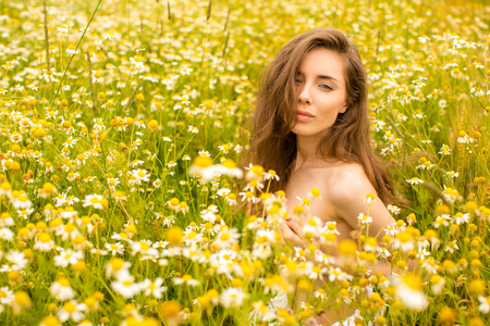 Sexy brunette young woman in chamomile field, cute female enjoying smell of daisy, sweet girl on flowers meadow, spring nature, having fun outdoorの写真素材