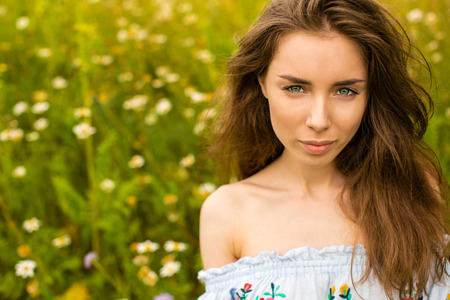 Photo of pretty brunette woman in chamomile field, cute female enjoying smell of daisy, sweet girl...