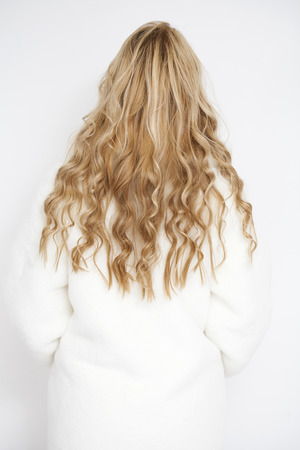 Female Long wavy blonde hair, rear view, studio wall backgroundの写真素材