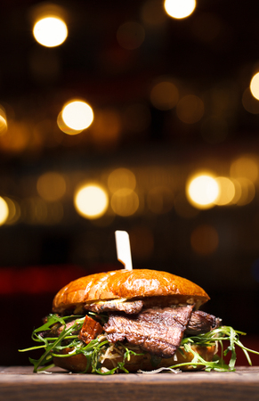 Burger with beef on wooden background. Fresh tasty hamburger with pork, cheese, tomato, onion and lettuce and french fries on a wooden table and dark background with copy space. Close upの写真素材
